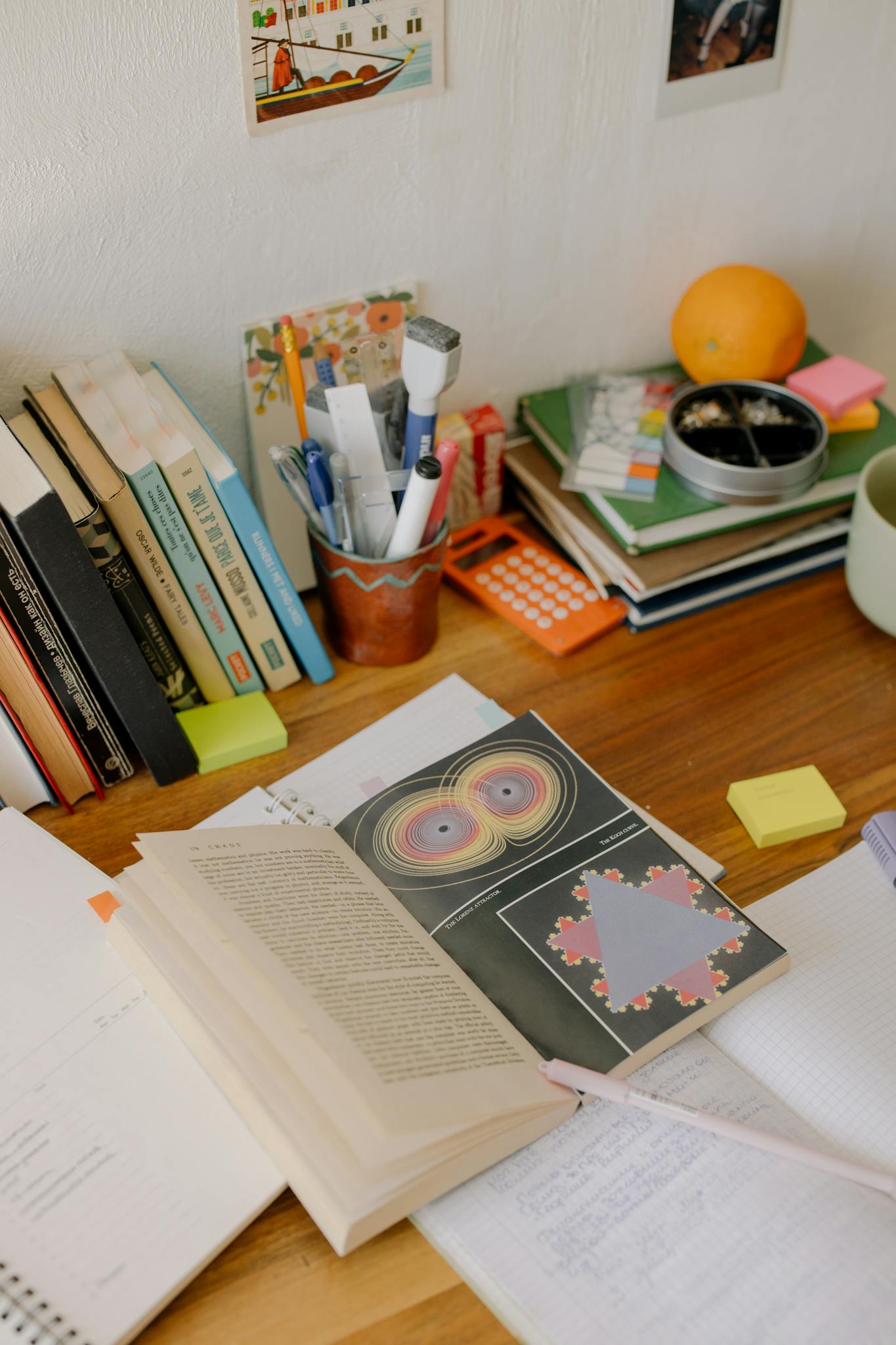 A study desk filled with open books, notebooks, and colorful stationery for academic work.